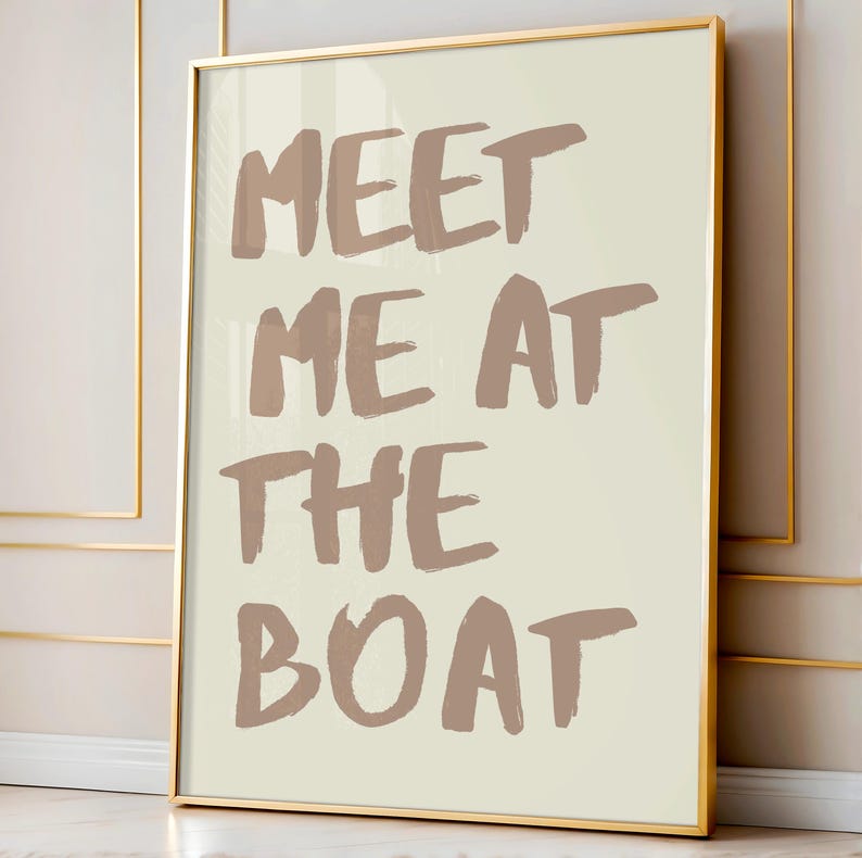 May include: A framed print with a beige background and brown text that reads "Meet me at the boat".