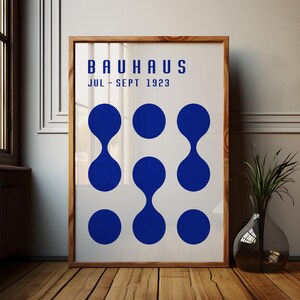 May include: A white poster with the text "BAUHAUS JUL - SEPT 1923" in blue. The poster features a design of nine blue circles with a teardrop shape in the center of each circle.