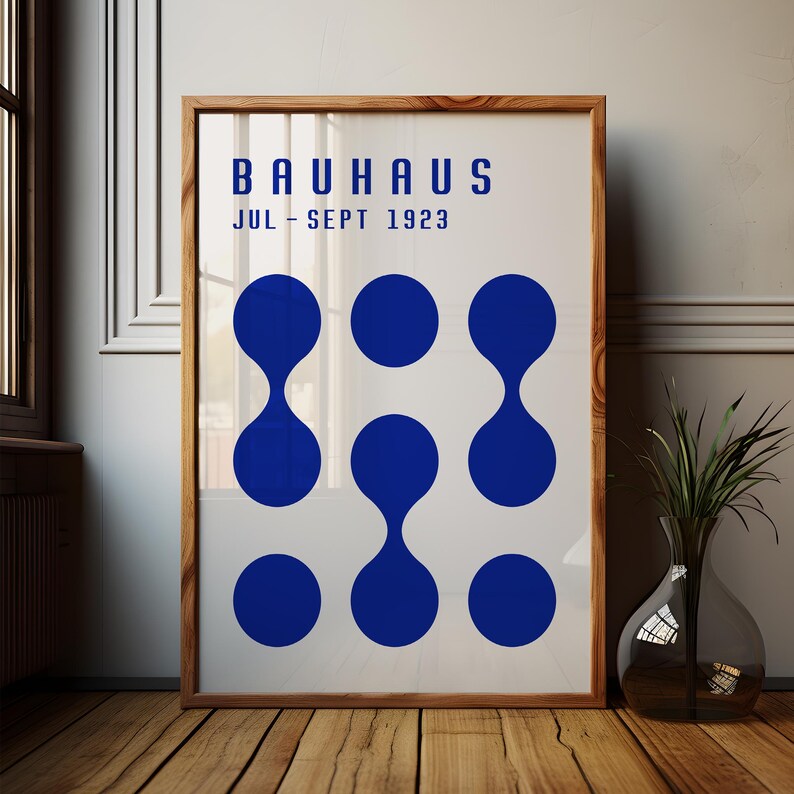 May include: A white poster with the text "BAUHAUS JUL - SEPT 1923" in blue. The poster features a design of nine blue circles with a teardrop shape in the center of each circle.
