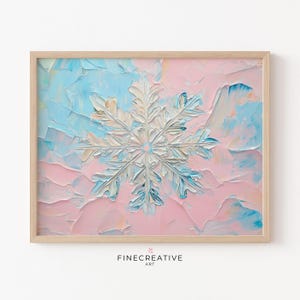 May include: A framed abstract painting of a white snowflake on a pink and blue background. The snowflake is painted in a textured style, giving it a 3D effect. The background is a mix of light pink and blue, with hints of yellow and orange.