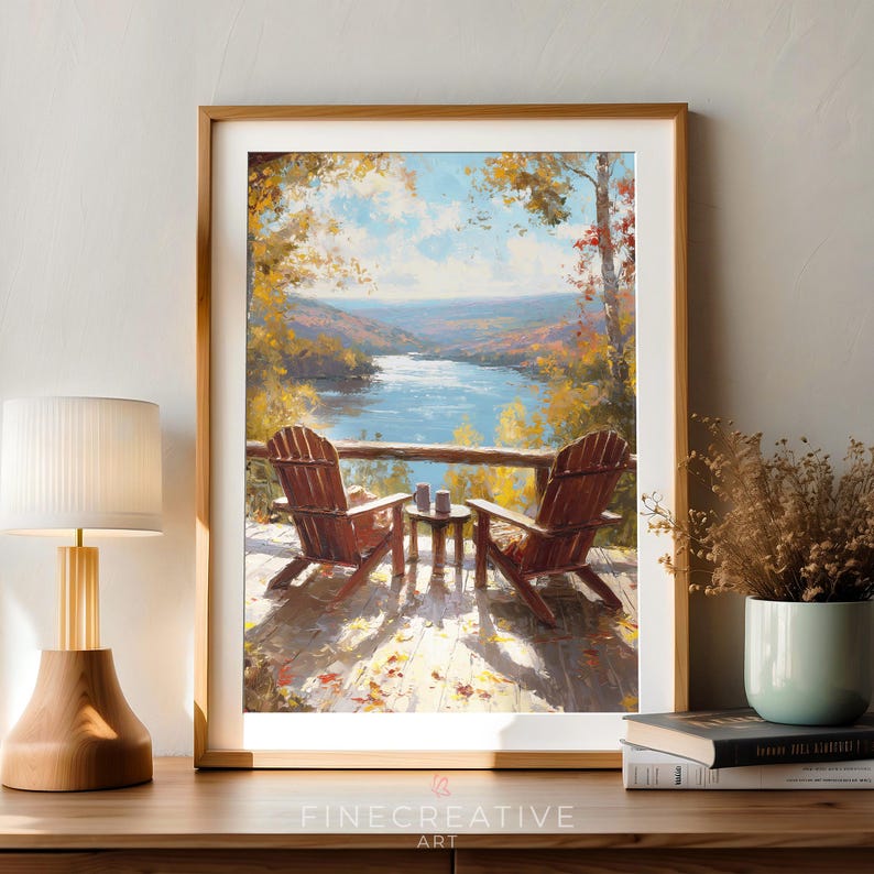 May include: A framed painting depicts a serene lakeside scene with two wooden Adirondack chairs on a deck. The artwork features a vibrant color palette of blues, greens, and autumn hues, with a small table between the chairs. The text "FINECREATIVE ART" is visible.
