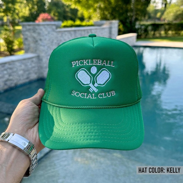May include: A kelly green trucker hat featuring white embroidered text that reads PICKLEBALL SOCIAL CLUB above and below a graphic of two crossed pickleball paddles and a ball. The hat has a structured front panel and a matching green brim.