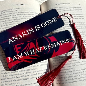 May include: Two rectangular bookmarks with dark backgrounds and red accents. The top bookmark features the white text "ANAKIN IS GONE" and the bottom bookmark features the white text "I AM WHAT REMAINS". Both bookmarks include a red tassel attached.