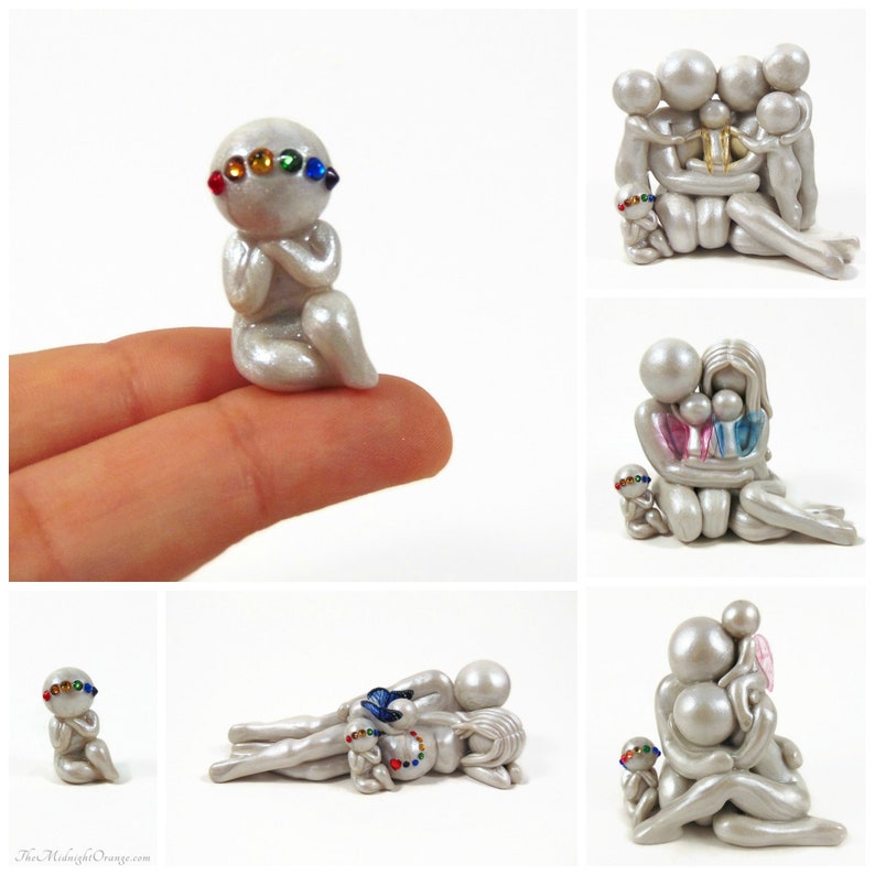May include: A collection of handmade, pearl-like figurines. The figurines depict abstract human forms in various poses, some embracing, others in prayer. Each figure has colorful gemstone accents, with a rainbow of colors.
