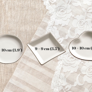 May include: Three white ceramic trinket dishes in round, diamond, and heart shapes. The round dish measures 10 x 10 cm (3.9 inches), the diamond dish measures 9 x 9 cm (3.5 inches), and the heart-shaped dish measures 10 x 10 cm (3.9 inches).