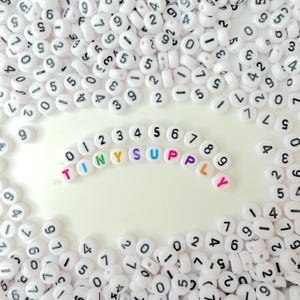 Cuentas redondas planas de acrílico blanco con números negros (7 mm x 3 mm)