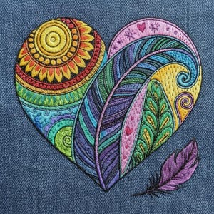 Puede incluir: Diseño de corazón bordado con colores vibrantes. El corazón presenta un motivo de sol, plumas y patrones intrincados en tonos de amarillo, naranja, verde, azul, morado y rosa. También hay una pluma morada separada. El diseño está sobre un fondo azul denim.