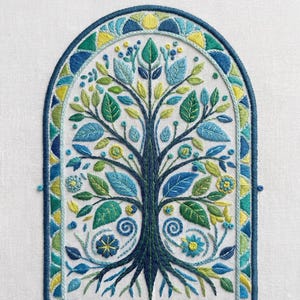 Pode incluir: Design de árvore bordada com tronco e galhos azul escuro, apresentando folhas e flores azuis, verdes e amarelas. A obra de arte é emoldurada dentro de um arco azul escuro, com fundo branco. O bordado mostra costuras detalhadas e um tema inspirado na natureza.