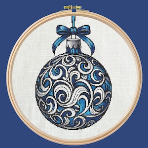 Peut inclure: Une boule de Noël bleue et blanche avec un motif en spirale. La boule est suspendue à un cerceau en bois.
