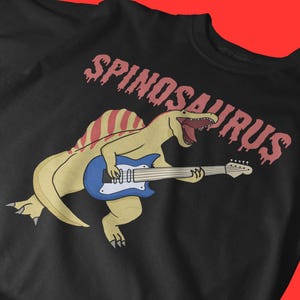 Spinosaurus Guitar Unisex T-Shirt, Funny Dinosaur Band Tee, Rock Music Graphic Shirt, Jurassic Metal Shirt for Musicians & Dino Lovers