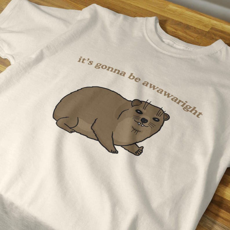 t-shirt with a cute hand-drawn hyrax illustration and the phrase ‘it’s gonna be awawaright’ — funny wholesome animal meme graphic tee.