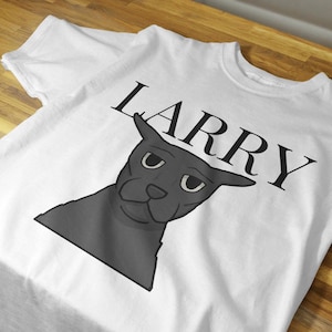 May include: White t-shirt featuring a cartoon illustration of a gray dog with the name "LARRY" printed above the dog's head in black capital letters. The dog has a slightly grumpy expression.