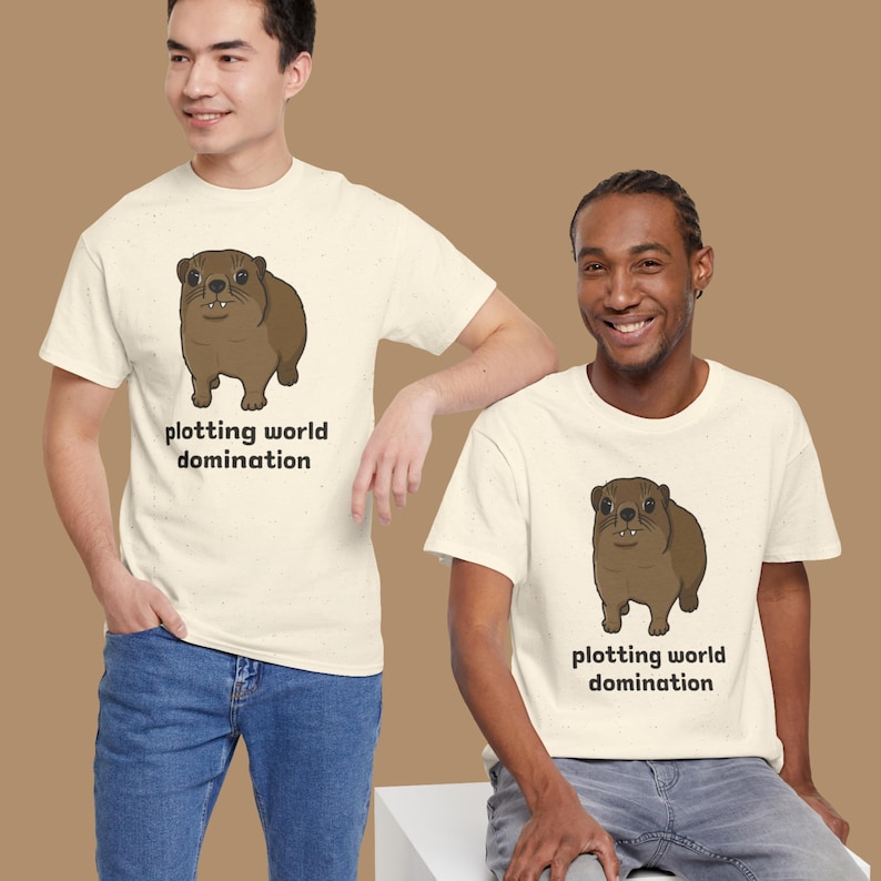 Cute brown hyrax illustration wearing a serious expression with the text “plotting world domination” printed on a t-shirt, funny animal meme graphic tee