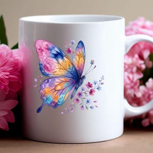 Puede incluir: Taza de cer&aacute;mica blanca con un dise&ntilde;o de mariposa en acuarela. La mariposa tiene alas en tonos rosa, azul, naranja y morado, con detalles florales. Peque&ntilde;as flores moradas y azules rodean la mariposa. La taza tiene un asa blanca.