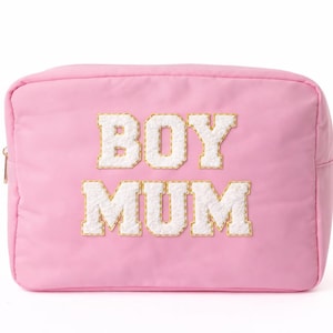 May include: A pink rectangular cosmetic bag featuring the text "BOY MUM" in white, textured, block letters with gold edging. The bag has a gold zip and is set against a white backdrop.