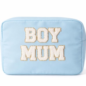 May include: A pale blue cosmetic bag featuring the text "BOY MUM" in white, sequined lettering. The bag has a gold zip and is rectangular. The material appears to be a smooth, possibly nylon, fabric.