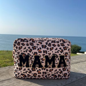 May include: Pink leopard print makeup bag with black velvet "MAMA" lettering.