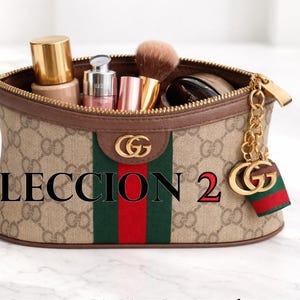 Può includere: Un beauty case beige con finiture marroni, striscia verde e rossa e dettagli dorati. La borsa è piena di prodotti per il trucco. Il testo "COLECCION 2" è visualizzato.