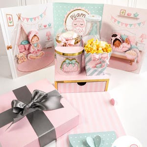 Puede incluir: Un set de fiesta que incluye una caja rosa con un lazo gris, un soporte con cajón a rayas rosas y blancas, un recipiente para palomitas, una botella transparente y tarjetas decorativas con ilustraciones de niños en pijama y el texto Pijam Party.