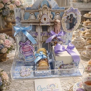 Puede incluir: Un juego de regalo decorativo con el tema de Bridgerton, que incluye macarons, una botella de champán y una imagen enmarcada. El juego incluye un vaso transparente, una caja blanca y una bandeja transparente, todos adornados con lazos azules y morados y motivos florales.