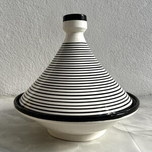 K&ouml;nnte beinhalten: Wei&szlig;e Keramik-Tagine mit einem schwarz-wei&szlig;en Streifenmuster und einem schwarzen Rand.
