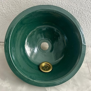 Può includere: Un lavandino in ceramica verde scuro con uno scarico in ottone.