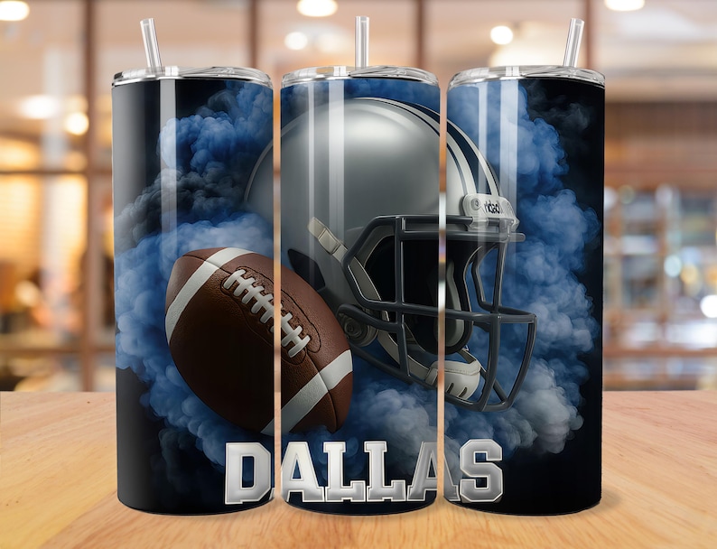 May include: A stainless steel tumbler featuring a football, helmet, and blue smoke design. The word "DALLAS" is displayed in silver block letters. The tumbler has a black lid and a clear straw.