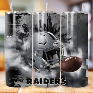 May include: Three stainless steel tumblers with a black and white design featuring a football helmet, a football, and the word "RAIDERS".