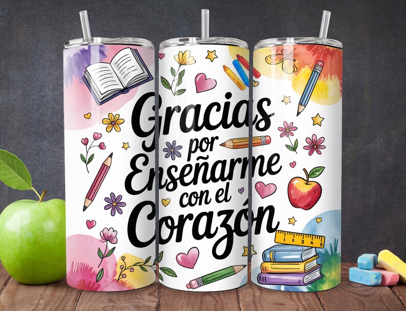 Pu&ograve; includere: Tre bicchieri in acciaio inox bianchi con disegni ad acquerello rosa, giallo e blu. I bicchieri presentano una variet&agrave; di illustrazioni a tema scolastico, tra cui libri, matite, righelli e mele. Il testo "Gracias por ense&ntilde;arme con el coraz&oacute;n" &egrave; stampato in nero sui bicchieri.