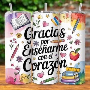 Pu&ograve; includere: Un bicchiere bianco con un design colorato che presenta un libro, matite, cuori, stelle e un righello. Il testo sul bicchiere recita "Gracias por ense&ntilde;arme con el coraz&oacute;n".