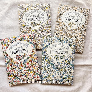 Può includere: Quattro quaderni decorativi in carta con disegni floreali e di pavoni. Ogni quaderno presenta il testo "Handmade with love in Italy" e "carta di FIRENZE" in un emblema circolare. I quaderni hanno motivi colorati.