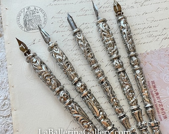 May include: A set of six silver ornate dip pens with intricate designs. The pens have a vintage aesthetic and are perfect for calligraphy or decorative writing.