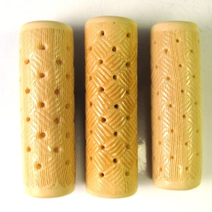 Puede incluir: Tres objetos cilíndricos beige con una superficie texturizada y múltiples agujeros. Los objetos están hechos de un material que se asemeja a la madera.