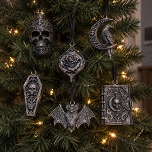 May include: A set of six hanging ornaments in a dark silver finish, featuring a skull, a crescent moon with a raven, a rose, a coffin with a skull and sword, a bat with wings spread, and a book with a skull and moon design on the cover.