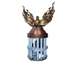 Op de afbeelding: Gedetailleerde sculptuur van een feniks met uitgespreide vleugels, bovenop een structuur in klassieke stijl. De feniks is goud en brons, met een vurig uiterlijk. De basis is lichtgrijs met witte zuilen en een wenteltrap.