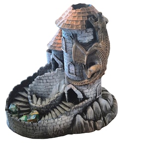 May include: A gray stone tower with a brown roof and a dragon wrapped around it. The tower has a spiral staircase leading up to the top. There are green and gold dice at the bottom of the tower.