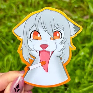 May include: A die-cut sticker featuring a stylized, light gray anthropomorphic cat character with large orange eyes, a pink nose, and a long pink tongue sticking out. The character is holding a white cigarette in its mouth, outlined in orange.