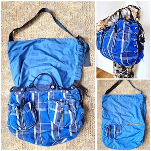 Puede incluir: Un bolso tote azul y blanco a cuadros con un bolsillo grande en la parte delantera. El bolso tiene un cierre de cordón y una correa larga.