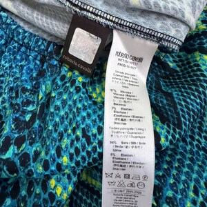 K&ouml;nnte beinhalten: Ein Roberto Cavalli Kleidungsst&uuml;ck mit einem lebendigen Schlangenmuster in Blau, Schwarz und Gelb. Das wei&szlig;e Pflegeetikett gibt 97% Viskose und 3% Elastan f&uuml;r den Au&szlig;enstoff sowie 94% Seide und 6% Elastan f&uuml;r das Futter an, inklusive Pflegesymbolen.