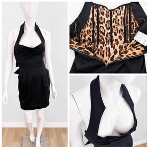 Könnte beinhalten: Ein schwarzes Neckholder-Minikleid mit strukturiertem Oberteil und herzförmigem Ausschnitt. Das Innenfutter zeigt ein braun-schwarzes Leopardenmuster, und an der Innenseite des Oberteils ist ein weißes Pflegeetikett deutlich zu erkennen.