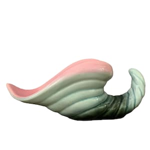 May include: A ceramic cornucopia in shades of pink, blue, and green. The horn-shaped vessel has a curved, open design with a smooth, glossy finish. The colors transition from pink to blue to green.