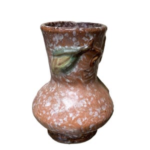 May include: A small, ceramic vase with a bulbous body and a flared rim. The vase is primarily a speckled orange-brown color with green and brown leaf accents. The vase is approximately 6 inches tall.