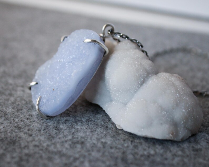 May include: A silver chain necklace with a light blue agate pendant and a white agate pendant.
