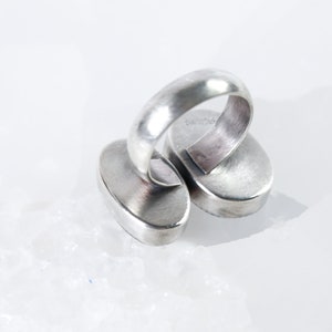 May include: Silver ring with two oval-shaped stones. The ring is marked "925" on the inside of the band.