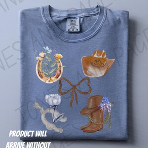 K&ouml;nnte beinhalten: Ein blaues T-Shirt mit Aquarellillustrationen eines Hufeisens mit Blumen, eines Cowboyhuts, einer Seil-Schleife, eines Spore mit einer Rose und eines Cowboy-Stiefels mit Blumen. Der Text "PRODUCT WILL ARRIVE WITHOUT WATERMARK" befindet sich unten.
