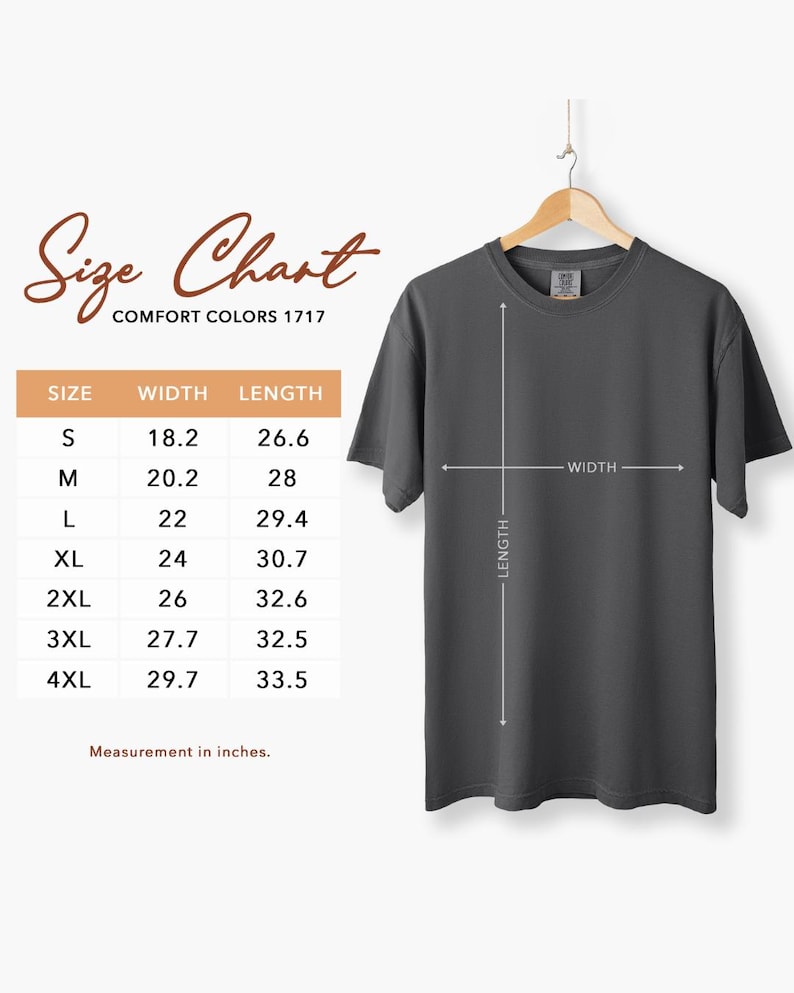 K&ouml;nnte beinhalten: Ein dunkelgraues Comfort Colors 1717 T-Shirt h&auml;ngt an einem Holzb&uuml;gel. Das Bild enth&auml;lt eine Gr&ouml;&szlig;entabelle mit Ma&szlig;en in Zentimetern: S (46.2cm Breite, 67.6cm L&auml;nge), M (51.3cm Breite, 71.1cm L&auml;nge), L (55.9cm Breite, 74.7cm L&auml;nge), XL (61cm Breite, 78cm L&auml;nge), 2XL (66cm Breite, 82.8cm L&auml;nge), 3XL (70.4cm Breite, 82.6cm L&auml;nge) und 4XL (75.4cm Breite, 85.1cm L&auml;nge).