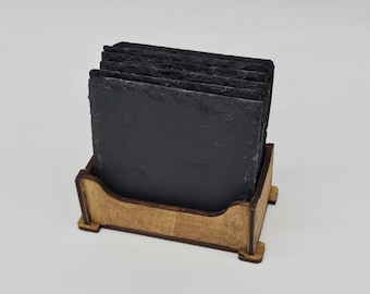 Peut inclure: Ensemble de dessous de verre carrés en ardoise noire aux bords rugueux, empilés dans un support en bois brun clair. Le support a un design rectangulaire simple avec de petits pieds. Les dessous de verre mesurent environ 10 cm de côté.