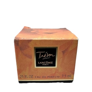 Könnte beinhalten: Ein kleiner, rechteckiger Karton von Lancôme Trésor Eau de Parfum. Die Schachtel hat eine warme, goldene Farbe mit einem schwarzen Etikett mit der Aufschrift "Trésor Lancôme Paris". Auf der Unterseite der Schachtel steht ".25 FL.OZ. EAU DE PARFUM 7,5 ml."
