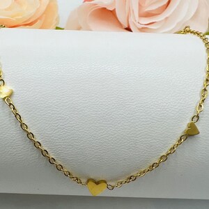 May include: A gold chain necklace with three small heart charms.