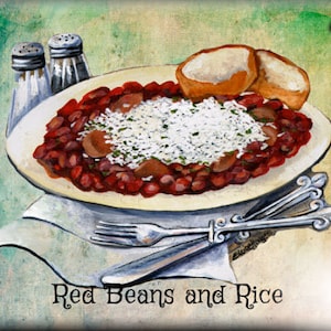May include: A white plate with red beans and rice, topped with white rice and two pieces of bread. The plate is on a brown surface with a white napkin and two salt shakers. The text "Red Beans and Rice" is written below the plate.